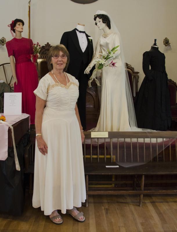 Edyie Johnson stands in front of her parents' wedding clothes wearing a dress that was her mothers. BY GEORGIA SPARLING